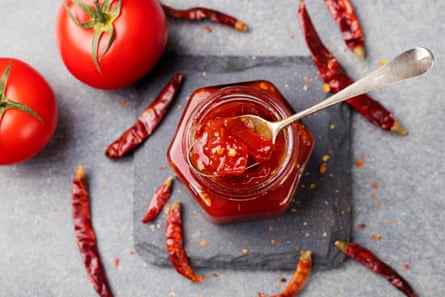 Tomato and chili sauce, jam, confiture in a glass jar on a grey stone background Top view