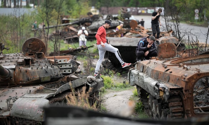 A group of young men inspect destroyed Russian battle tanks and armoured vehicles laying beside a road in Irpin, Ukraine.