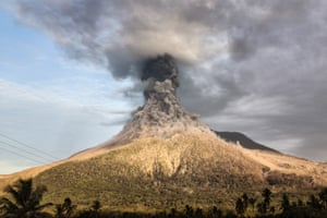 Thick clouds of grey and black smoke climb from the mouth of the volcano