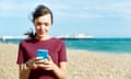 Woman using smart phone on beach.<br>GettyImages-629639551