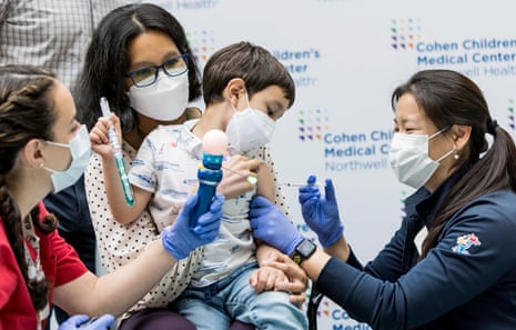 Dr. Sophia Jan (R) administers a coronavirus vaccination to Kevin Lazarus, 4, of Jackson Heights, Queens, while he is held by his mother, Dr. Mariecel Pilapel at the Cohen Children's Medical Center at Long Island Jewish Medical Center in the Queens borough of New York