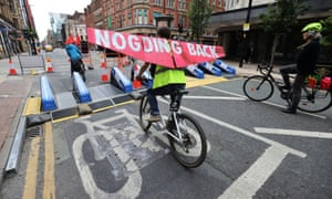 A cyclist rides along Deansgate in Manchester with a banner, after the road was closed to traffic in a plan to pedestrianise parts of the city centre.