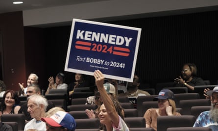 person in an auditorium holding up a kennedy 2024 sign