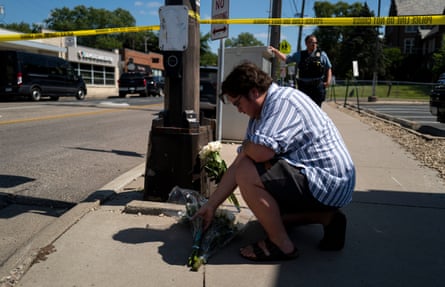 A man lays down white flowers next to yellow caution tape
