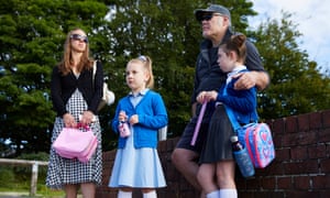 Two adults and two children leaning against a low brick wall