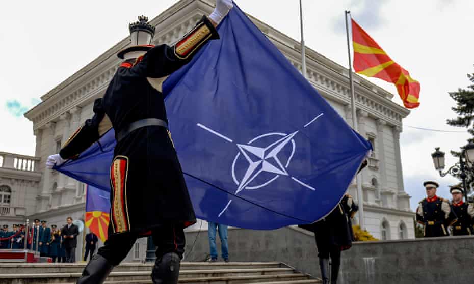 Members of an honour guard hoist the Nato flag in front of the government building in Skopje