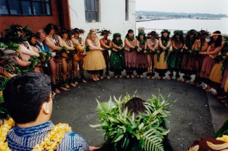 A circle of hulu performers in hulu dress on an outdoor stage.