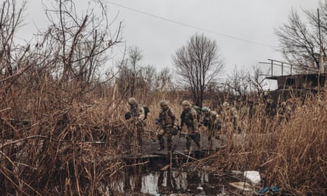 Ukrainian troops cross a damaged bridge to the front line in Bakhmut, eastern Ukraine, amid fierce fighting