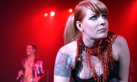 Jake Shears and Ana Matronic of Scissor Sisters on tour, with Ana pictured in close-up, showing her tattoo on her left shoulder, and Jake in the background