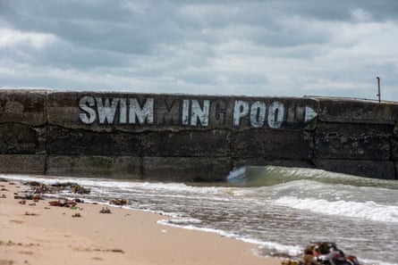 Image of a sea wall with graffiti ‘swim in poo’