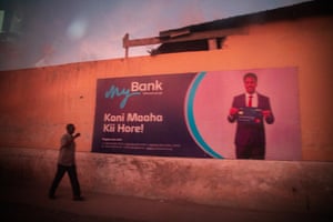 A man walks along a pavement next to a wall with an advert for MyBank