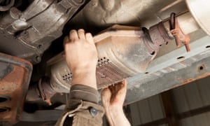 A SUV’s catalytic converter is being removed at a salvage yard.