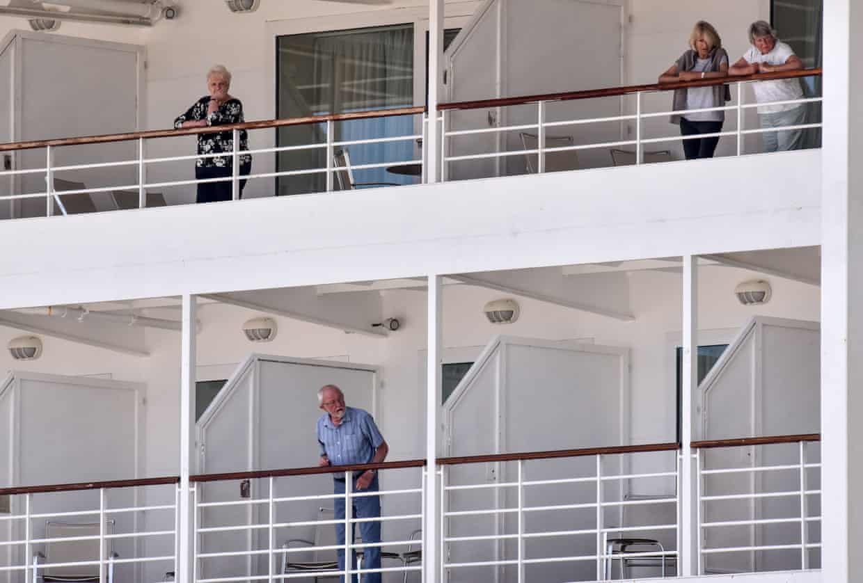 Cruise ship passengers stand on balconies, waiting to disembark in Cuba