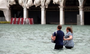 A couple walks in the flooded Saint Mark’s Square during a seasonal high tide in Venice.