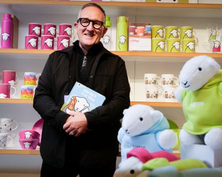 Man stands among sheep-themed mugs and soft toys in a shop