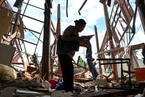 The silhouette of a woman holding belongings, in the shell of a destroyed house