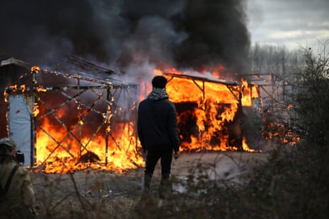 A man watches a hut burn as police officers clear part of the Calais refugee camp in France on 29 February
