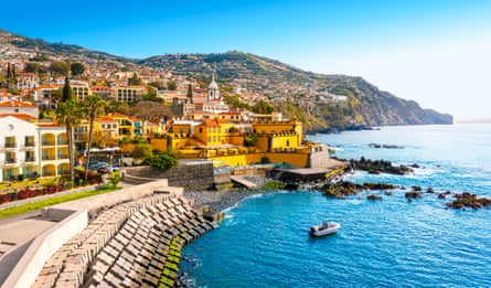 A sunny town with yellow buildings on a hill by the sea