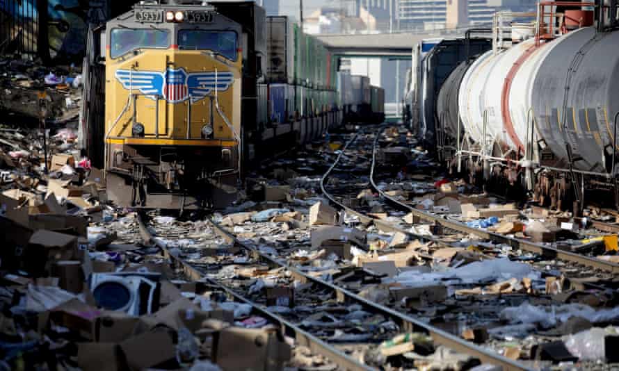 A Union Pacific freight train navigates tracks littered with shredded boxes and packages stolen from cargo containers that stop to unload in LA.