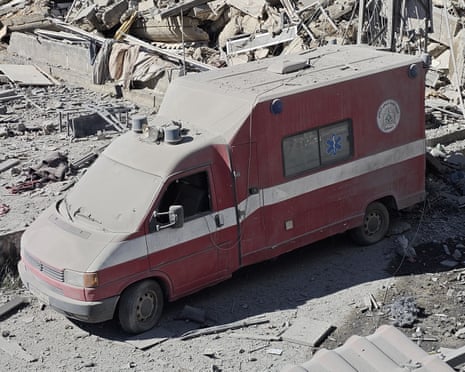 Ambulance covered in dust amid rubble