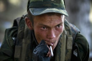 A Russian soldier in green fatigues lights a cigarette just outside Gori