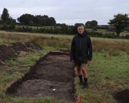Mark Merrony standing next to a rectangular scrape in a field