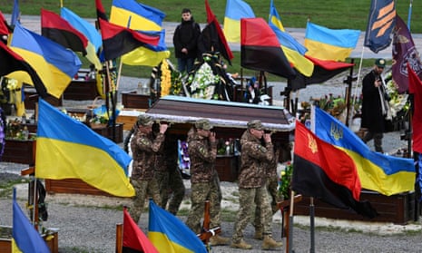 Ukrainian soldiers carry a coffin through a cemetery filled with the country’s flags