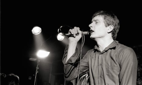 Ian Curtis performing live onstage at a Joy Division concert.