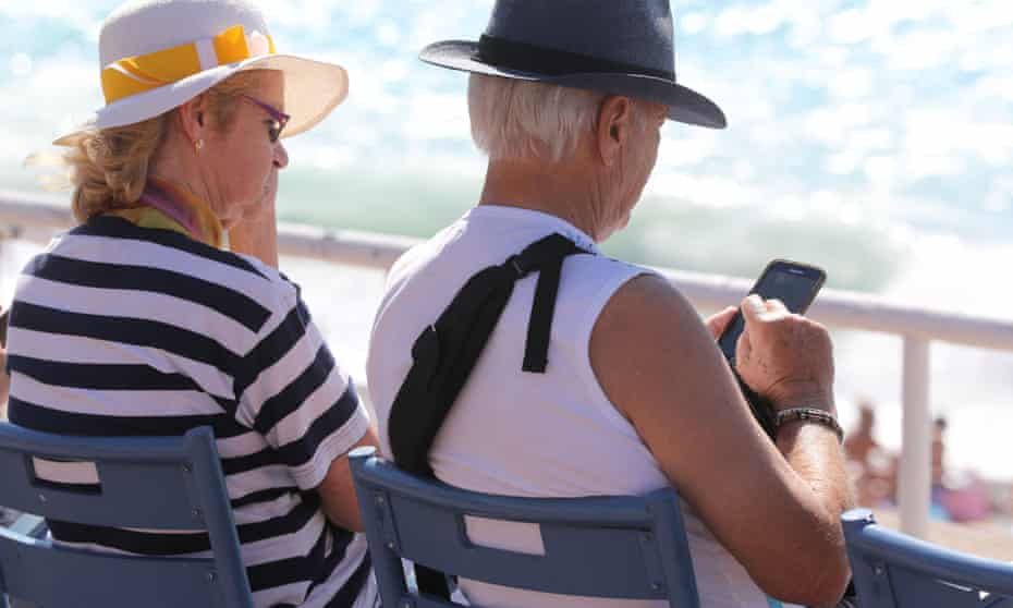 A man using a mobile phone while sitting beside a companion on the Promenades des Anglais beachfront in the French riviera city of Nice.