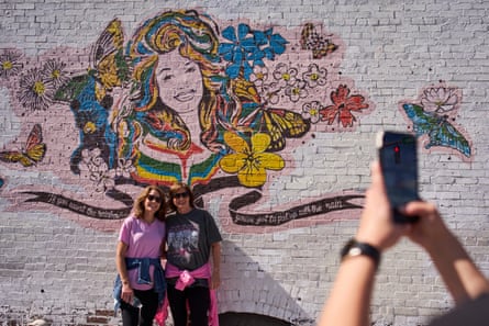 Two women airs for a representation successful beforehand of a Dolly Parton mural.
