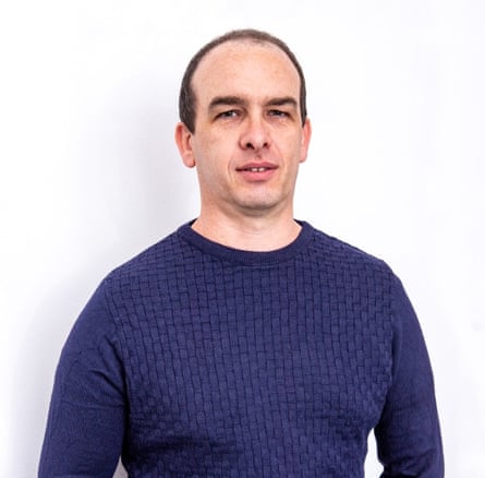 Marco Camurri, with short hair, wears a navy jumper in a portrait photo