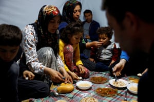 Salih with his mother Asli Dogru, his sister Zuleyha, his aunt Hatice Dogru, his uncle Ali Dogru, his cousin Ertugrul, and to the right, in silhouette, his father Emrullah Dogru, 37, have dinner together in a tent