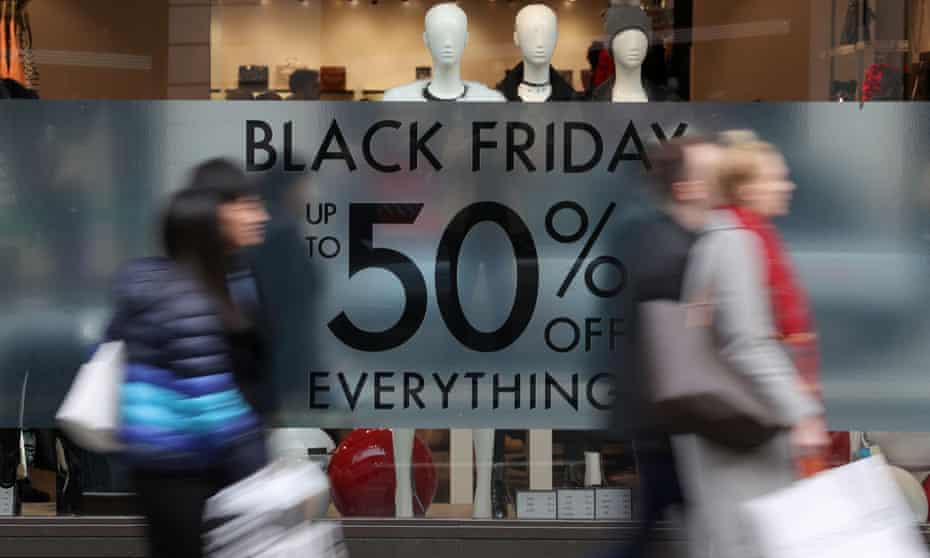 Shoppers pass a promotional sign for Black Friday sales discounts on Oxford Street in London.
