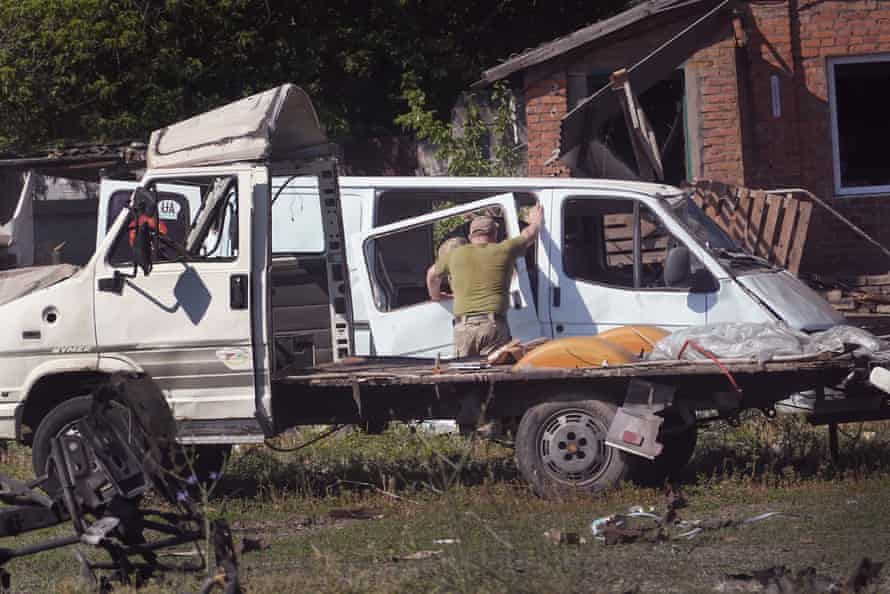 Des soldats enquêtent sur les dommages et récupèrent des objets après qu'un projectile et un incendie ont détruit un entrepôt à Druzhkivka.