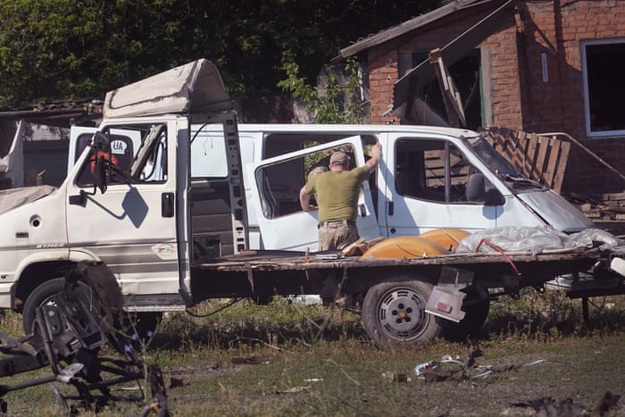 Soldiers survey damage and salvage items after a projectile and subsequent fire destroyed a warehouse building in Druzhkivka.