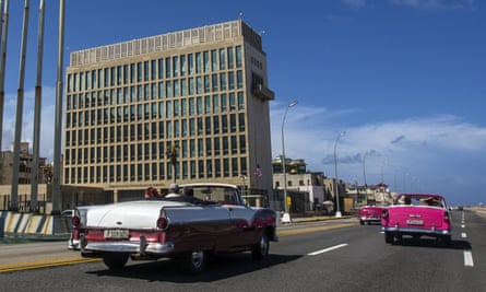 Tourists ride classic convertible cars on the Malecón beside the US embassy in Havana, Cuba.