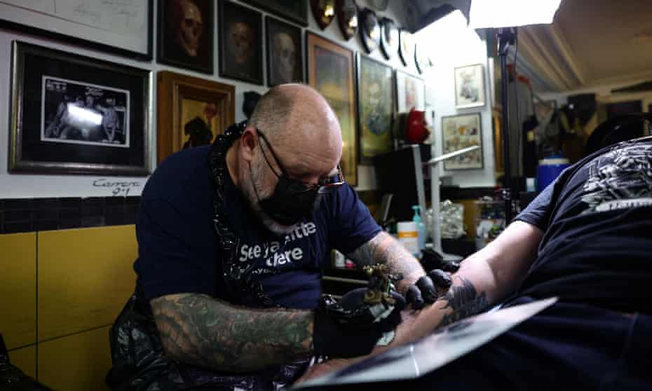 Tin-Tin, head of the French tattoo artists union, attends to a customer in his tattoo studio in Paris