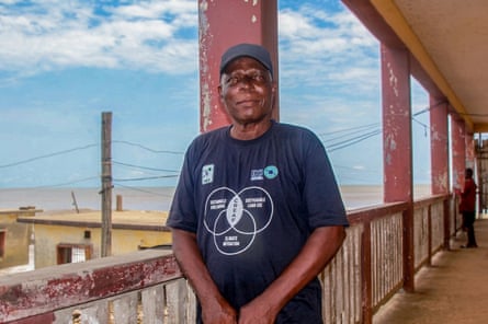 Lawrence Lemanu standing on the balcony of a large house with a sea view.