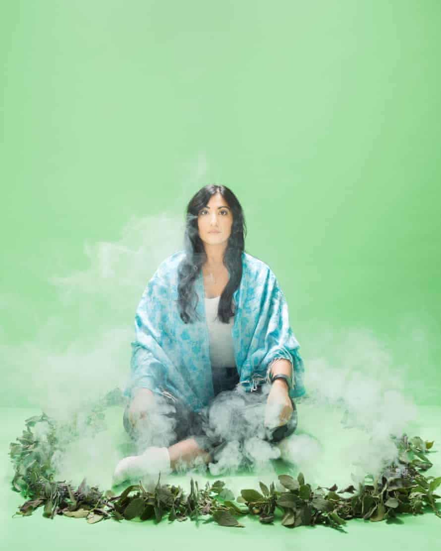 Guardian writer Coco Khan sitting in a circle of smoking leaves, against a green background