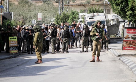 Israeli soldiers guard Jewish settlers who launched an attack on the Palestinian town of Deir Sharaf in the northern West Bank on 2 November.