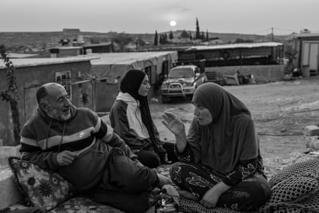 Ibrahim with his wife and daughter drink tea on the porch of their land