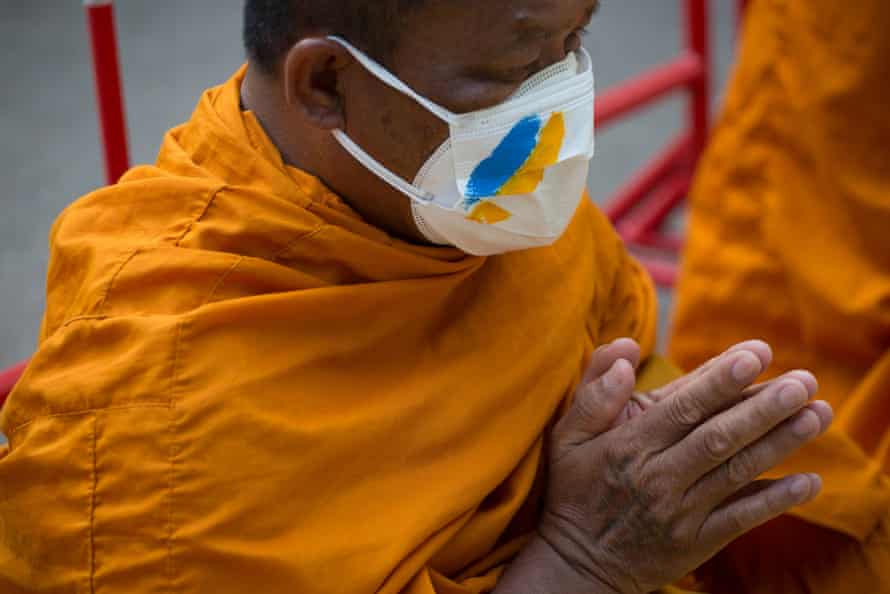 A monk with a Ukrainian flag mask prays in front of the Russian embassy in Bangkok on 19 March.