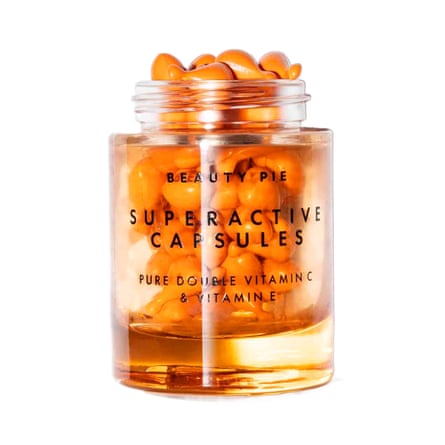 An open jar of Beauty Pie Superactive capsules. The jar is clear and the capsules orange.