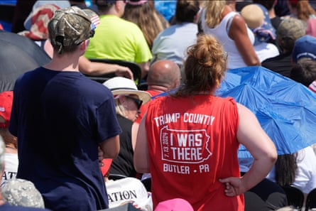 two people viewed from back in crowd. one wears shirt saying ‘trump county - butler county - i was there, 7-13-24’