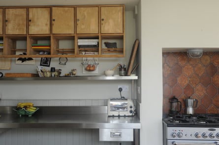 A freestanding oven with spanish tile splashback, some steel shelves and old school locker cupboards.