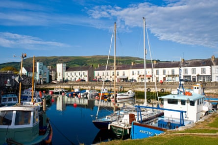 Colourful fishing boats sit in a harbour in front of a line of white terraced cottages