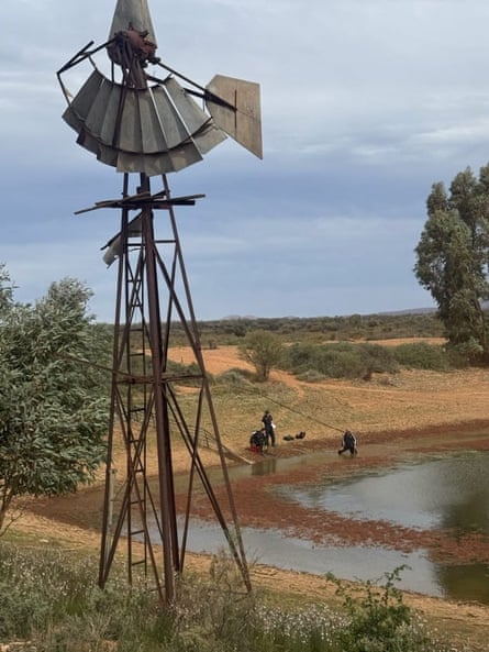 Police searching a dam with a broken windmill in the foreground