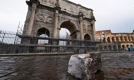 Fragments of Constantine's Arch lie on the ground in front of the 1,700-year-old structure with the Colosseum in the background
