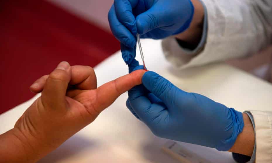 A person undergoes a finger prick blood sample as part of an antibody rapid serological test for Covid-19.