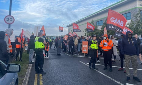 Striking Amazon workers holding GMB union flags on a road outside the online retailer’s vast BHX4 warehouse in Coventry.